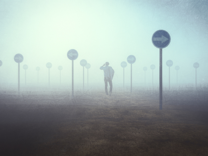 Man wandering lost among different signposts