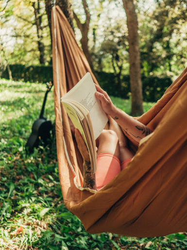 Person reading in a hammock in woodland