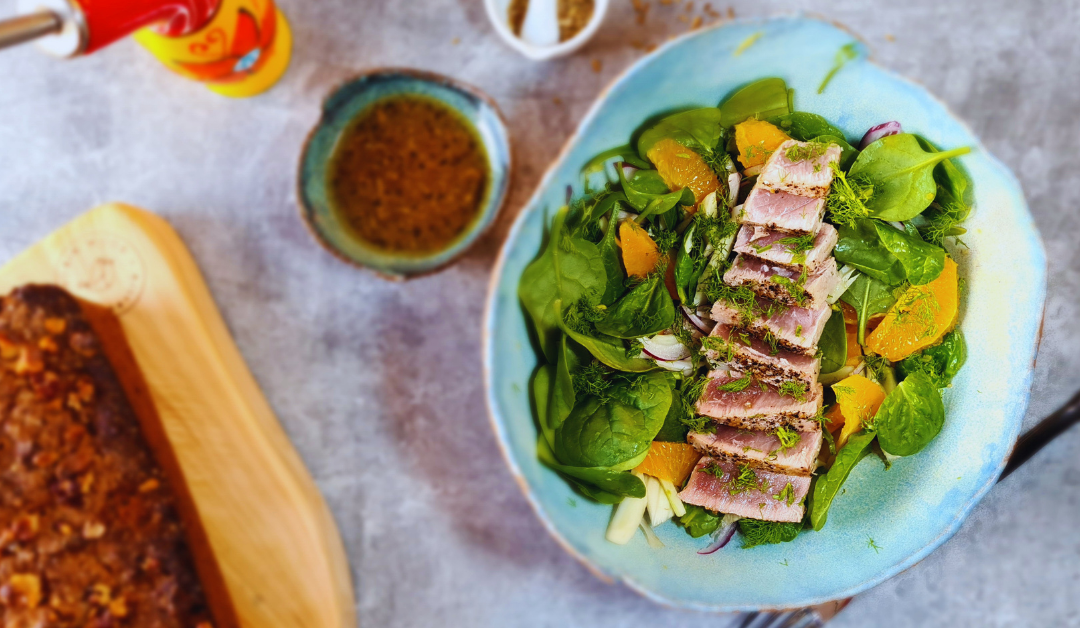 Gut Healthy salad recipe - seared tuna salad with spinach fennel and orange on a table with orange fennel dressing an date loaf