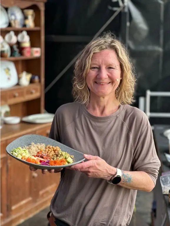 Nikkie, on the Chef's Kitchen Stage at the Big Retreat Festival holding a healthy plate of food