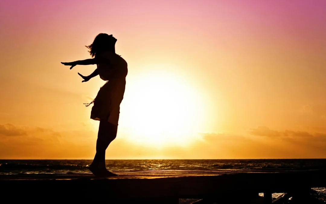 Woman at sunset flinging her arms and head back