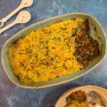 Lentil and sweet potato Farmer’s Pie in a turquoise oven dish, topped with golden mashed sweet potato and sprinkled with fresh parsley.