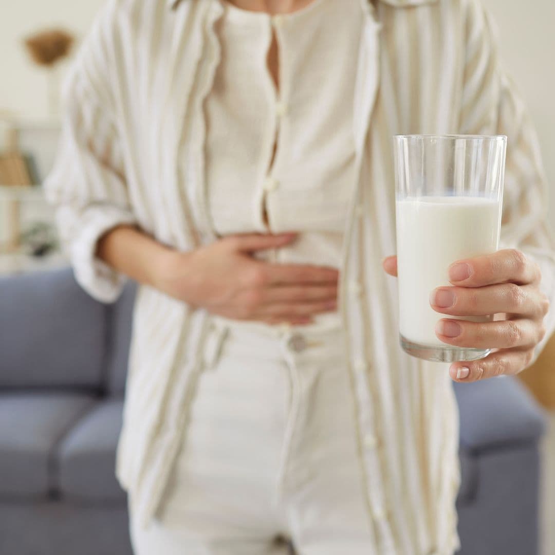 800x800 Woman holding stomach and glass of milk – illustrating causes of bloating beyond food such as intolerance and gut imbalance.