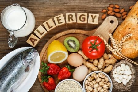Assortment of common allergenic foods such as nuts, eggs, milk, and seafood on a table with the word “Allergy” — representing food allergies as one possible cause of bloating beyond food sensitivities.