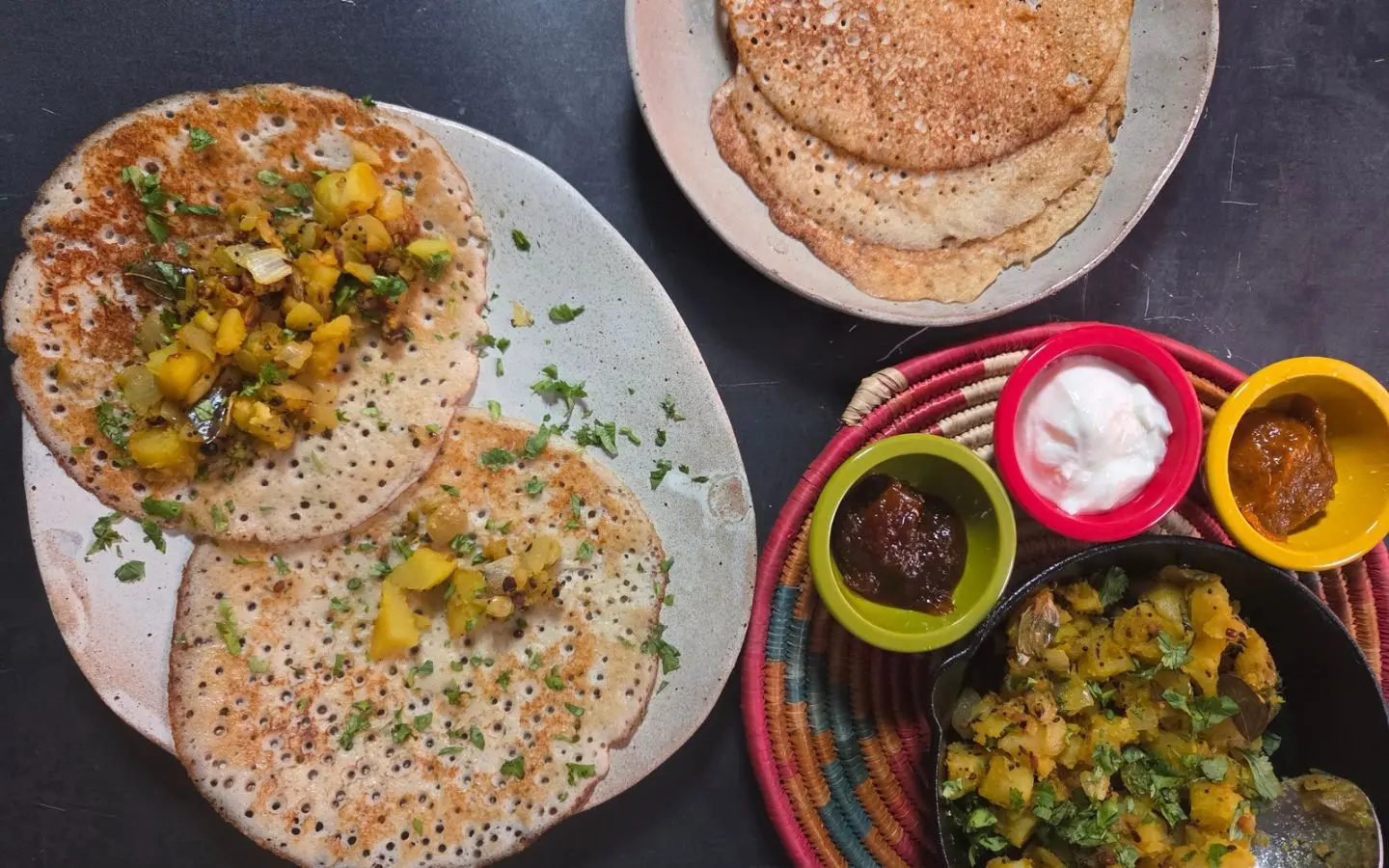 800x800 A plate of dosas, a pan of aloo masala, pickles, chutney and yogurt and a plate pulling it all together